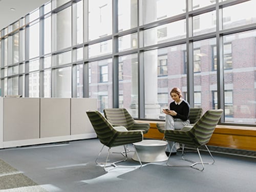 Equipe sentada ao redor da mesa trabalhando em laptops e smartphones utilizando uma integração da Vonage