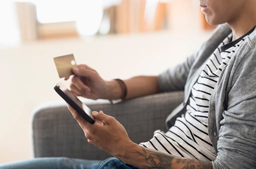 man shopping on mobile device at home holding credit card man shopping on mobile device at home holding credit card